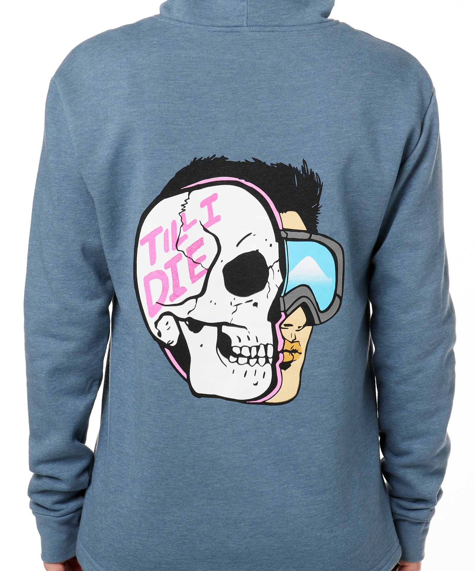 FEMALE MODEL WEARING A BLUE HOODIE WITH THE HOOD UP, FEATURING A GRAPHIC OF A CARTOON HALF SKELETON HALF SKIER HEAD WITH THE WORDS 'TILL I DIE'