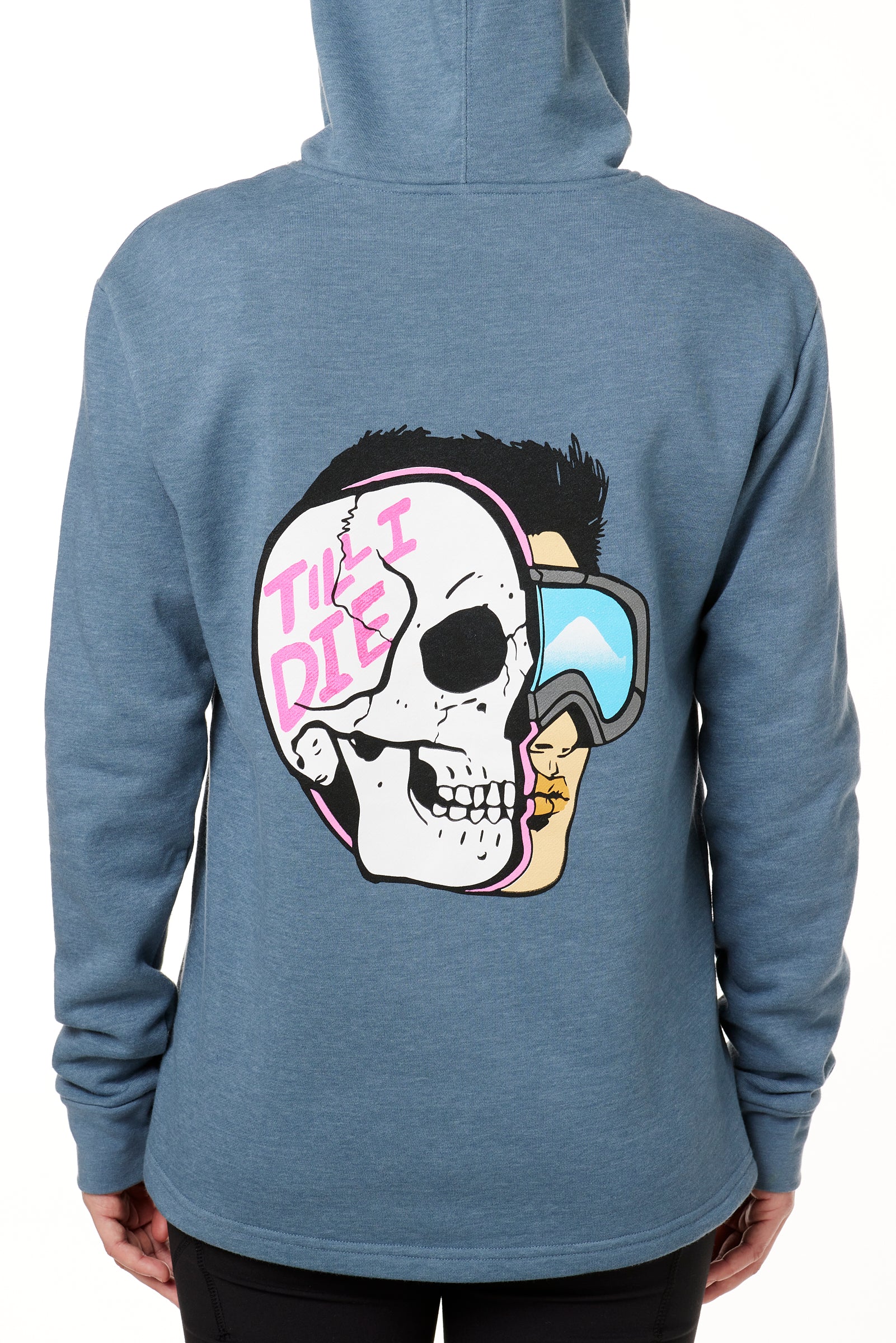 FEMALE MODEL WEARING A BLUE HOODIE WITH THE HOOD UP, FEATURING A GRAPHIC OF A CARTOON HALF SKELETON HALF SKIER HEAD WITH THE WORDS 'TILL I DIE'