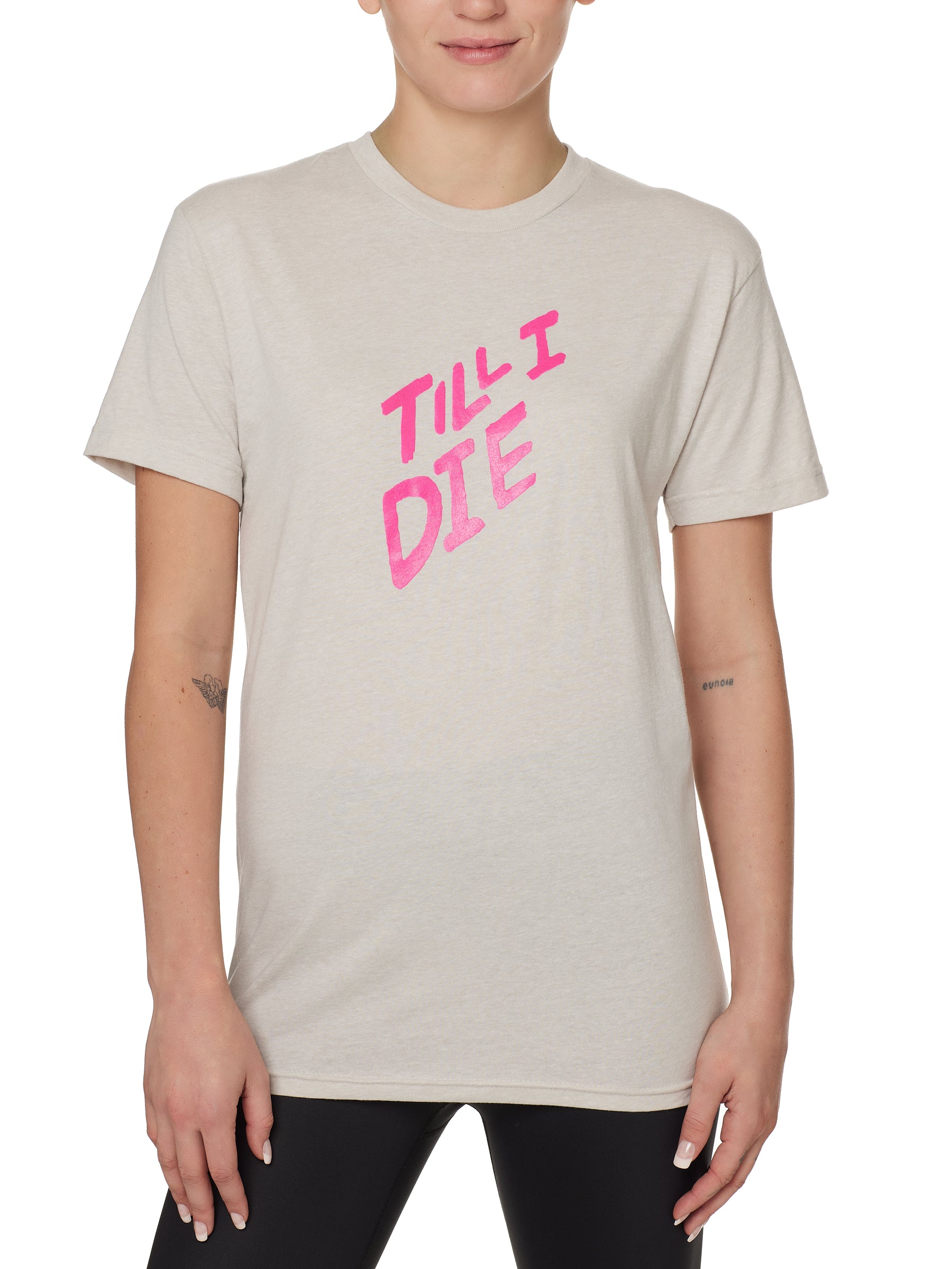 FEMALE MODEL WEARING A TAN TEE SHIRT WITH A THE WORDS TILL I DIE IN NEON PINK