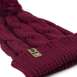 A close up of a burgundy cable-knit beanie hat with a matching pom-pom on top and a ribbed cuff featuring a Till I Die Logo leather tab, shown against a plain white background.