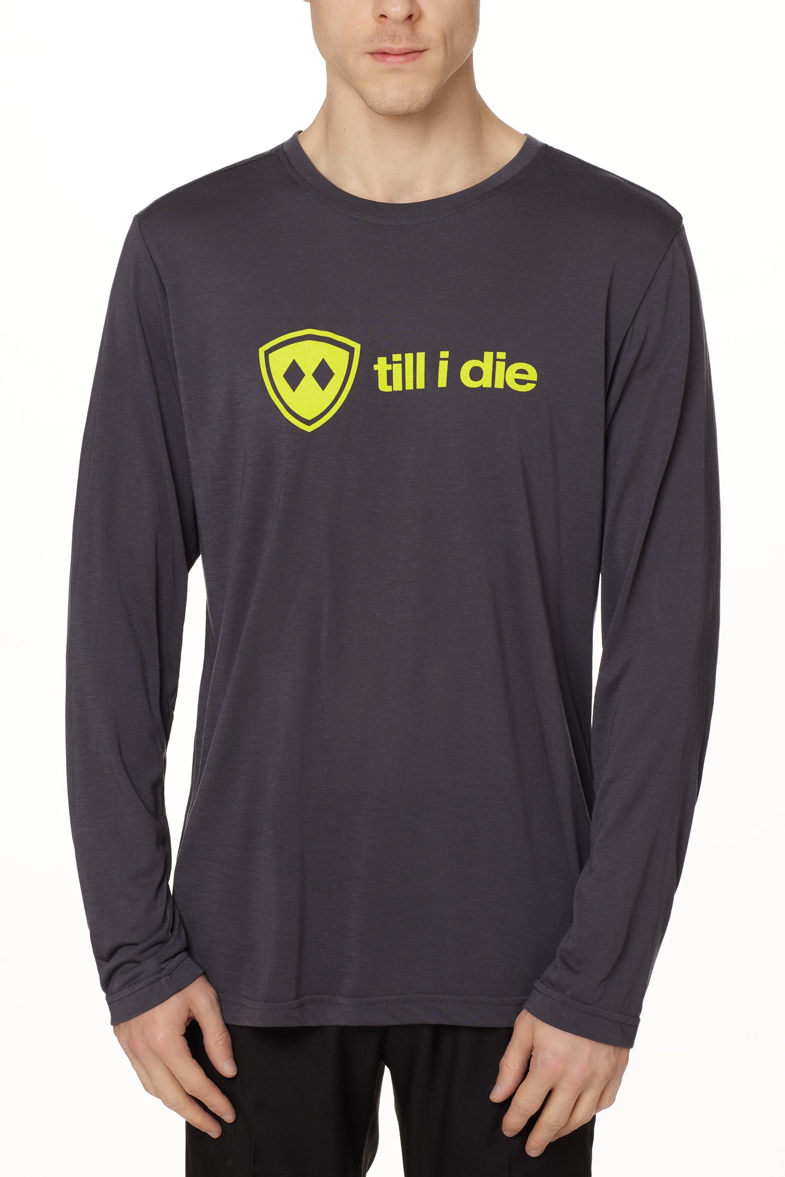 front view of a male model wearing a gray long sleeve tee with a bright yellow till i die logo across the chest