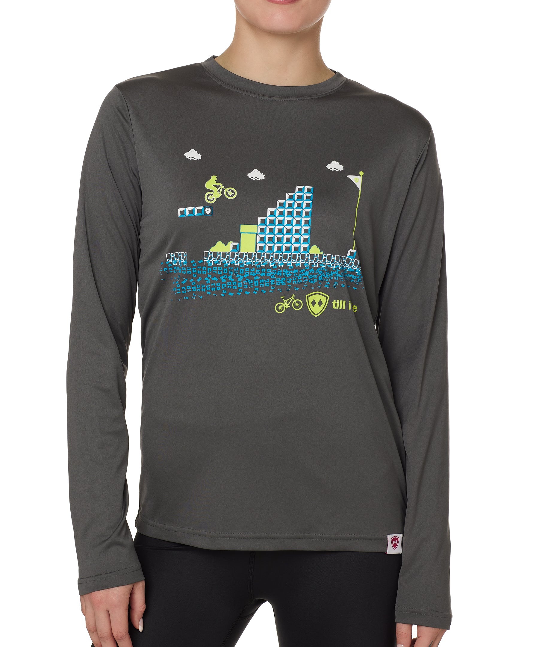 front view of a female model wearing the Mario Excite bike long sleeve performance in gray. The lime green and blue graphic features a retro 8-bit inspired graphic across the chest. The design mimics 1980s Mario Bros-style gameplay, with a biker jumping over ramps toward the goal pole.