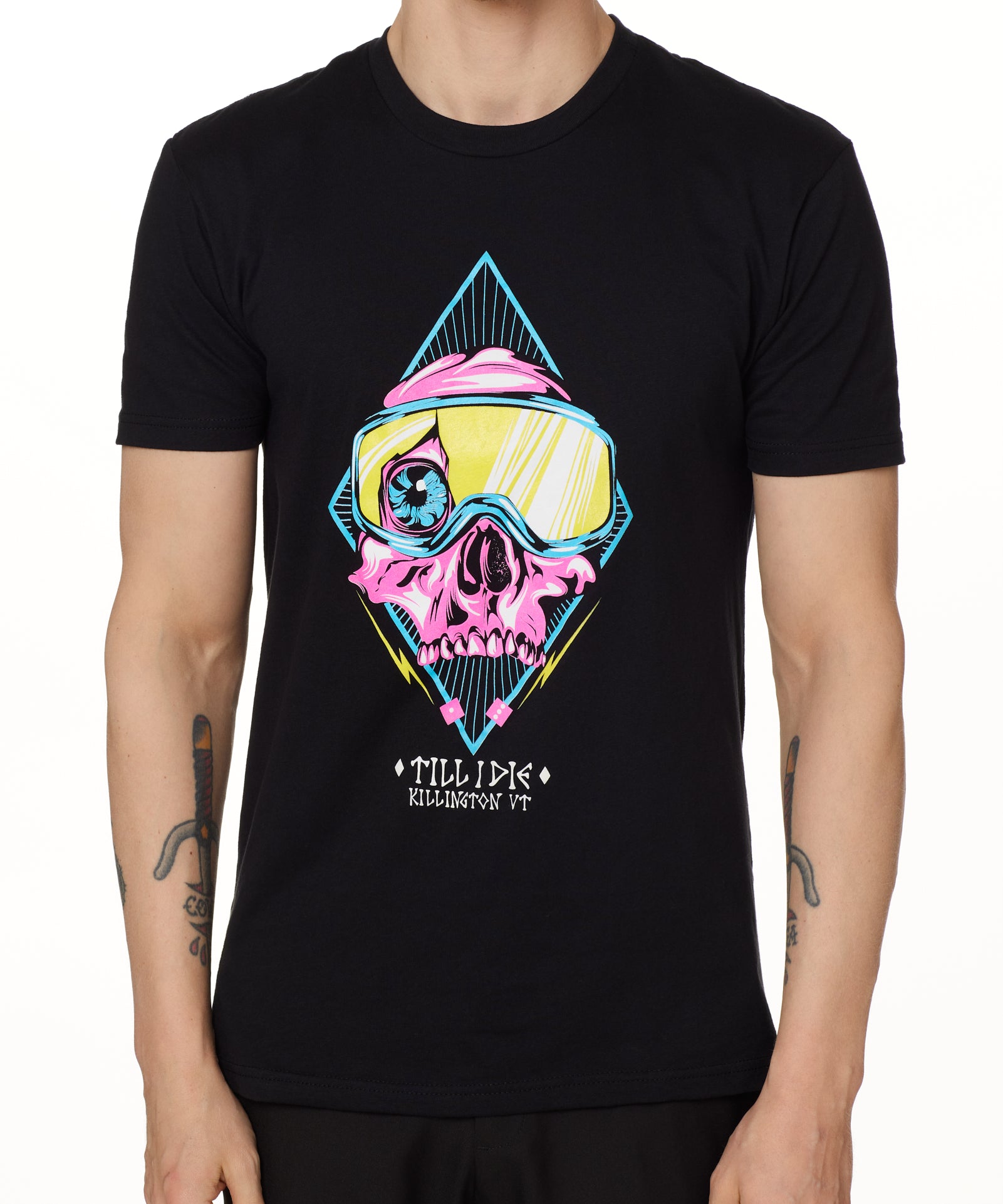 Front view of a male model wearing the Lucky 13 crew neck tee in black. The graphic features a pink skull with a cracked goggle lens revealing a wide eye, layered over a blue geometric pattern and yellow lightning bolts. “Till I Die” and “Killington, VT” text sit below the artwork.