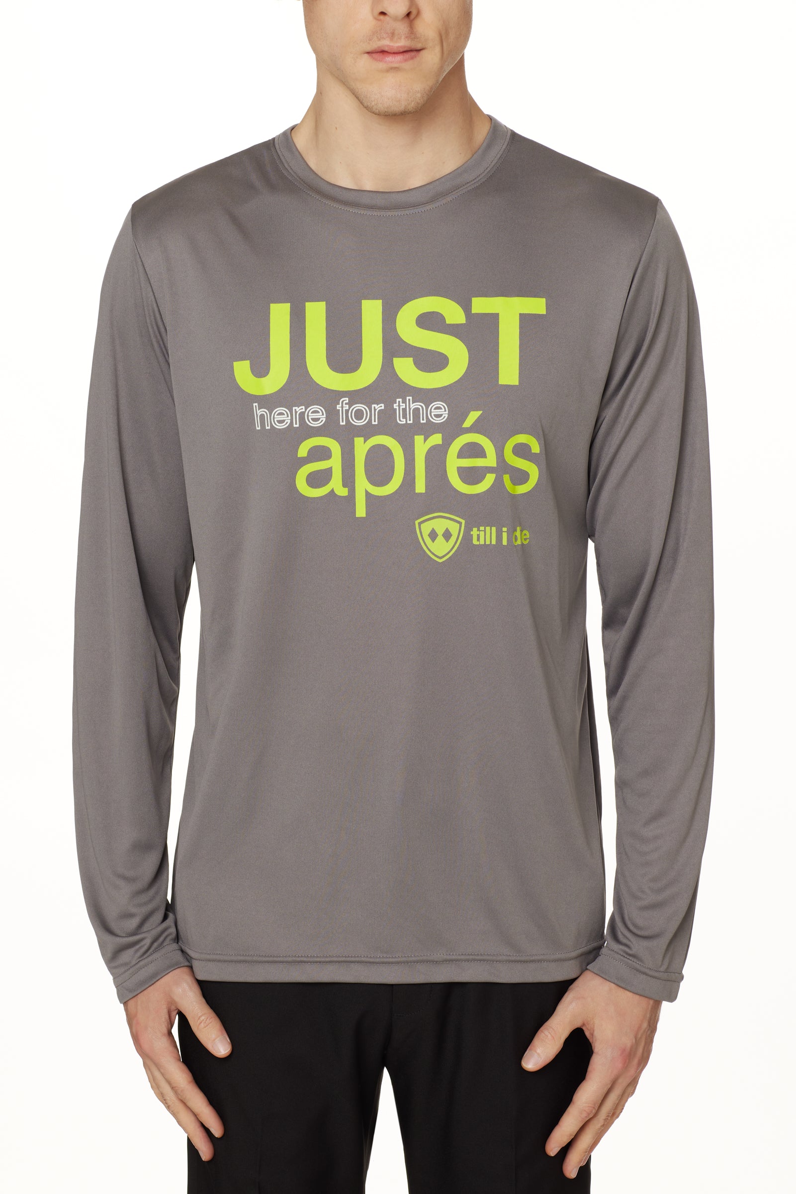 Front view of a male model wearing the Après Long Sleeve Performance Shirt in grey, displayed on a white background. The graphic features bold lime green and white text reading “Just here for the après,” with the Till I Die logo positioned below.