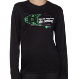FEMALE MODEL WEARING A BLACK LONG SLEEVE PERFORMANCE SHIRT WITH A GRAPHIC OF A SKI BINDING TUNED TO 11 WITH THE WORDS "ASK ME ABOUT MY DIN SETTING"