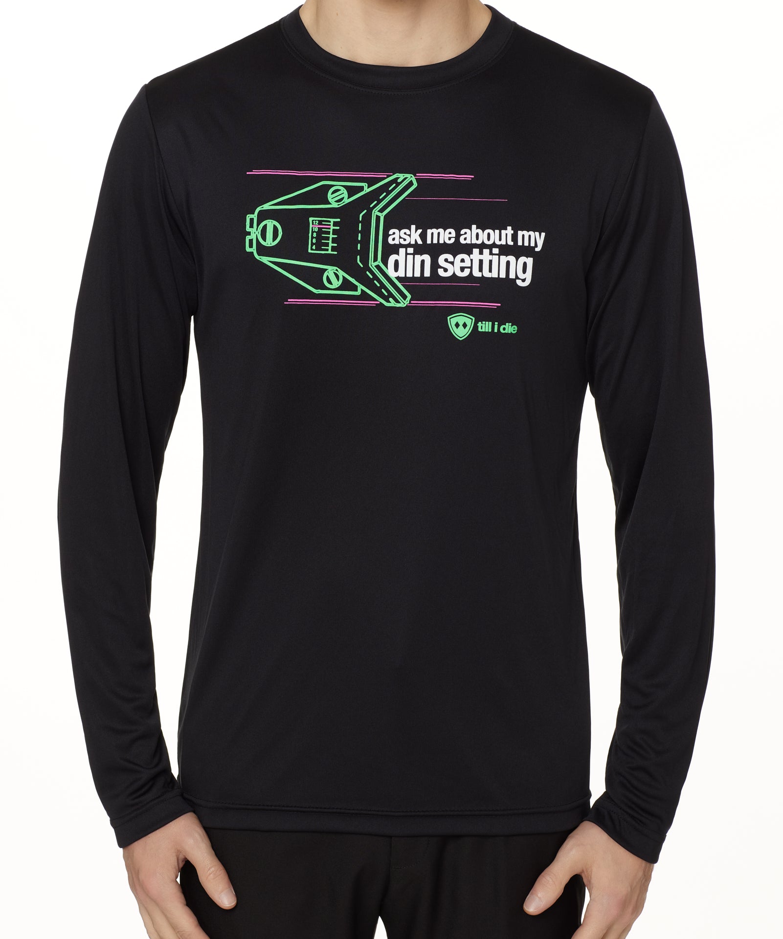 MALE MODEL WEARING A BLACK LONG SLEEVE PERFORMANCE SHIRT WITH A GRAPHIC OF A SKI BINDING TUNED TO 11 WITH THE WORDS "ASK ME ABOUT MY DIN SETTING"