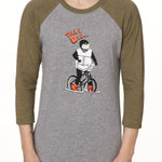 Front view of a male model wearing the Two Dollars Raglan 3/4 sleeve tee. The shirt features military green sleeves and a heather gray body, with a graphic of a ski biker in a full-face helmet. Above the illustration is “Till I Die…” text.