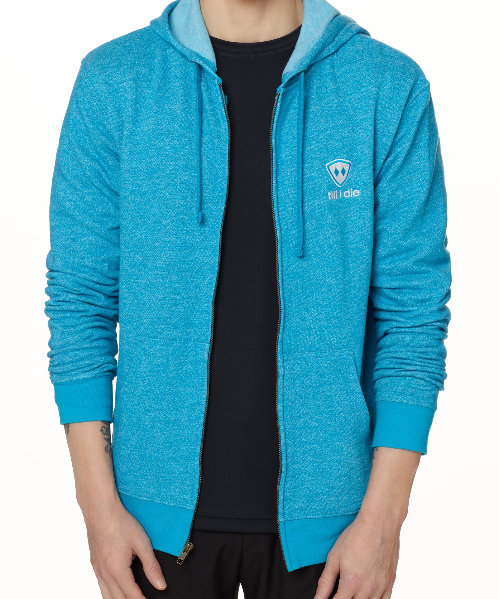 A MALE MODEL WEARING A HEATHER TEAL ZIP HOODIE WITH THE TILL I DIE EMBROIDERED IN WHITE AND TEAL
