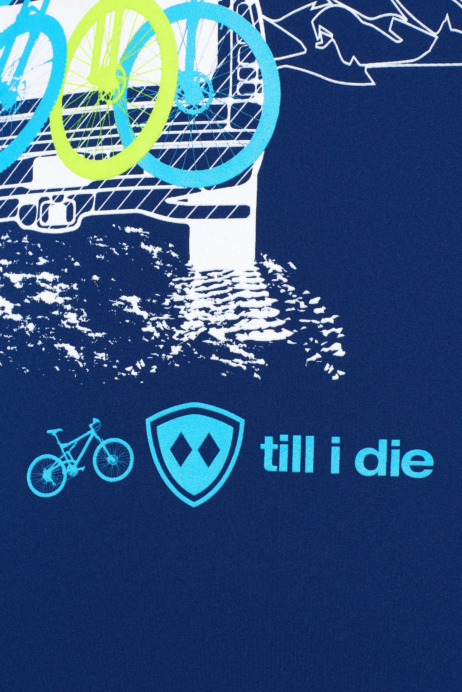 DETAIL OF A BLUE PERFORMANCE SHIRT WITH a light blue TILL I DIE LOGO AND BIKE GRAPHIC