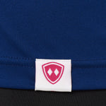 DETAIL OF A BLUE PERFORMANCE SHIRT WITH THE TILL I DIE SHIELD LOGO ON A WOVEN HEM TAG