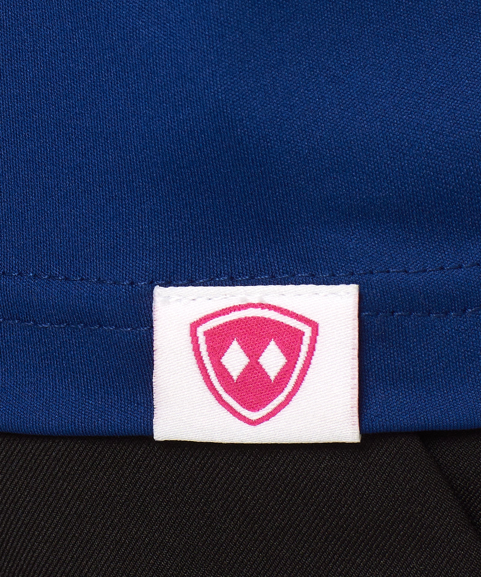 DETAIL OF A BLUE SHIRT WITH THE TILL I DIE SHIELD WOVEN HEM TAG