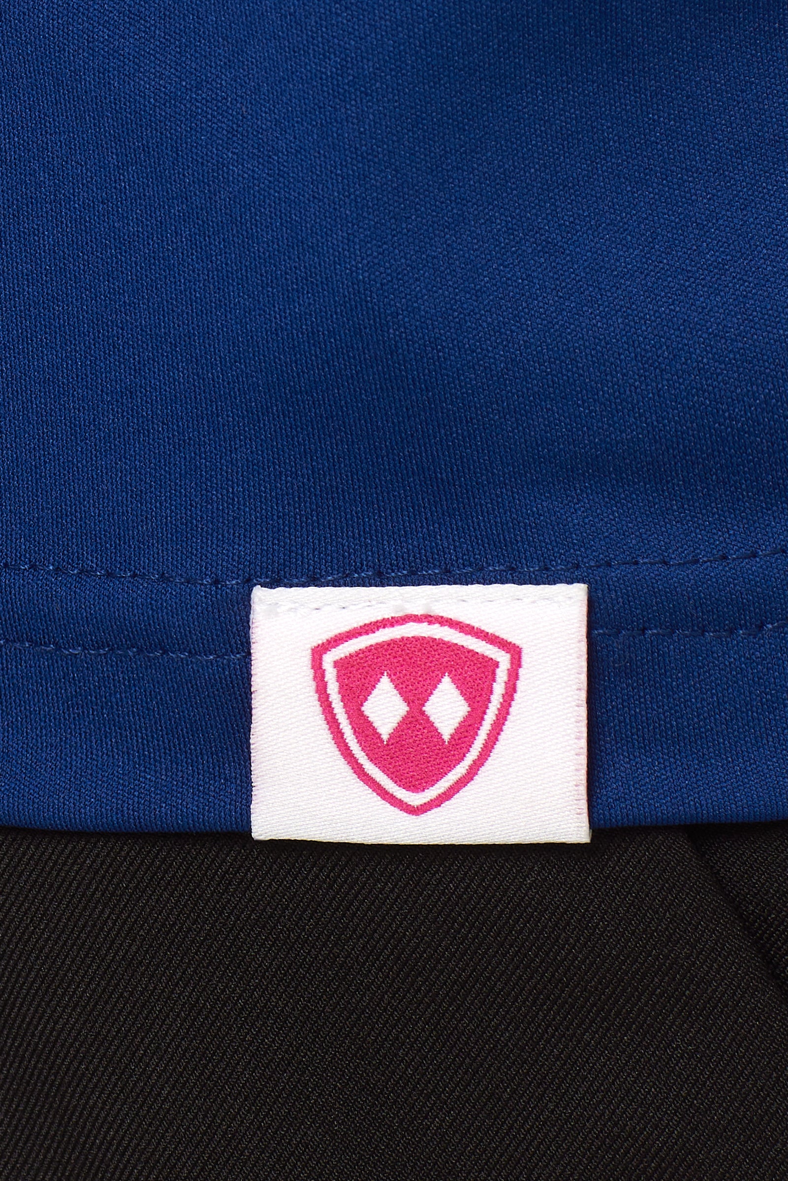 DETAIL OF A BLUE SHIRT WITH THE TILL I DIE SHIELD WOVEN HEM TAG