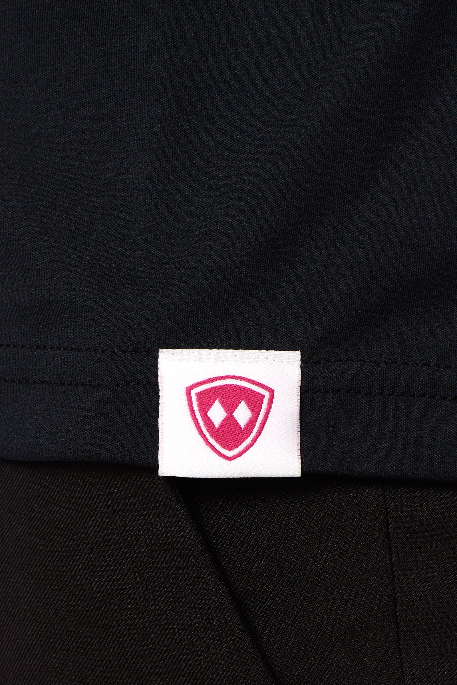 DETAIL OF A BLACK SHIRT WITH THE TILL I DIE LOGO HEM TAG