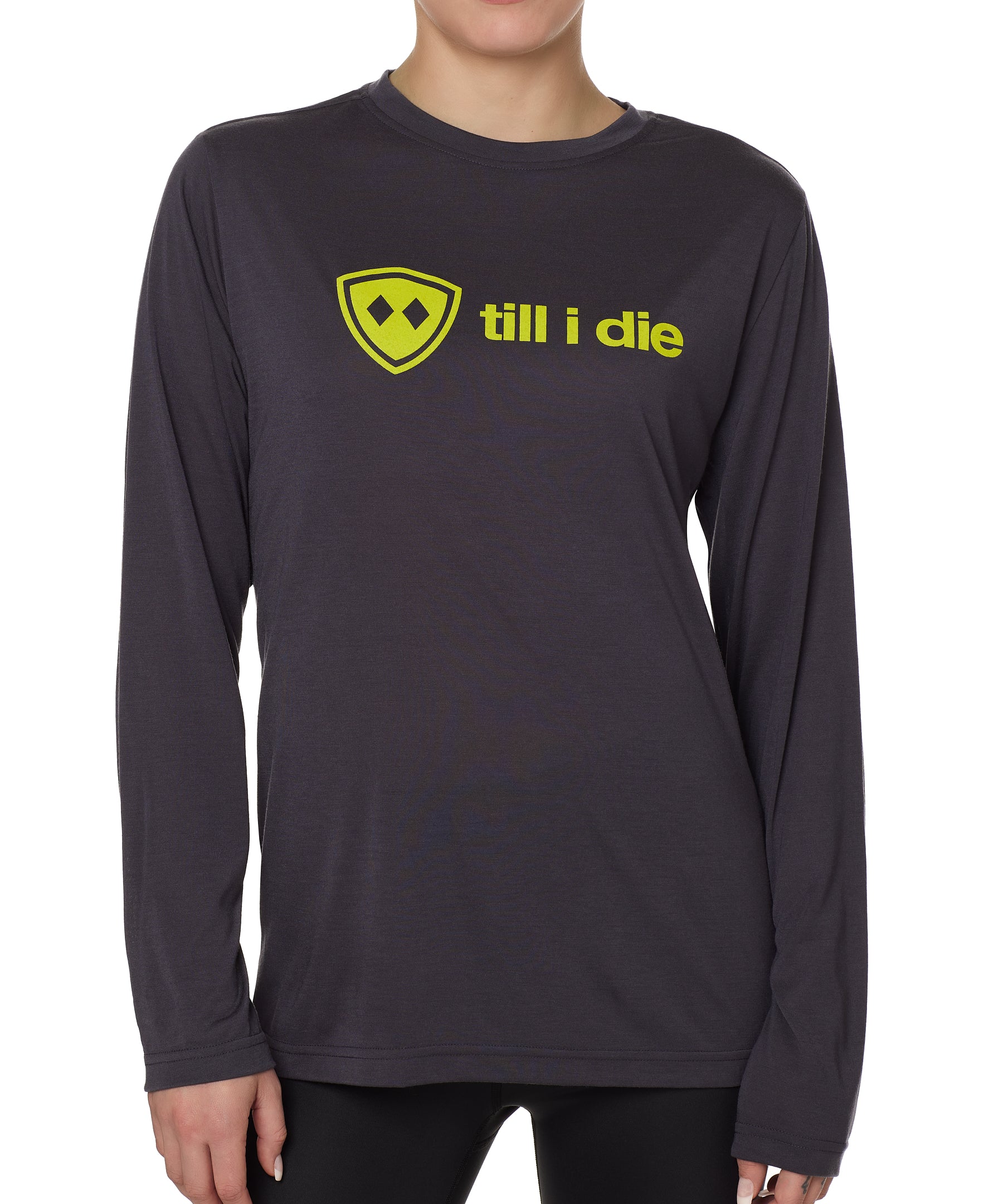 front view of a female model wearing a gray long sleeve tee with a bright yellow till i die logo across the chest