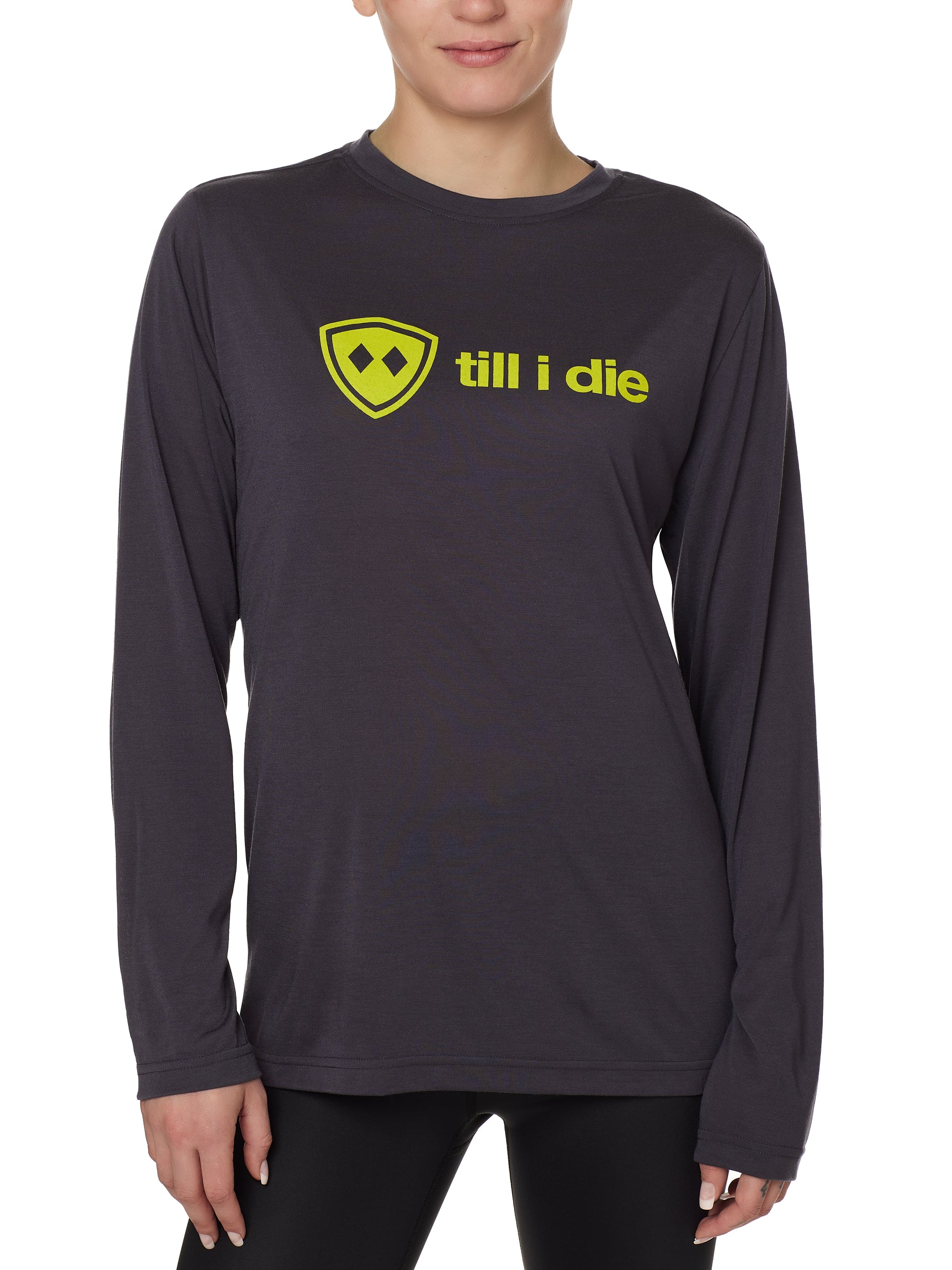 front view of a female model wearing a gray long sleeve tee with a bright yellow till i die logo across the chest