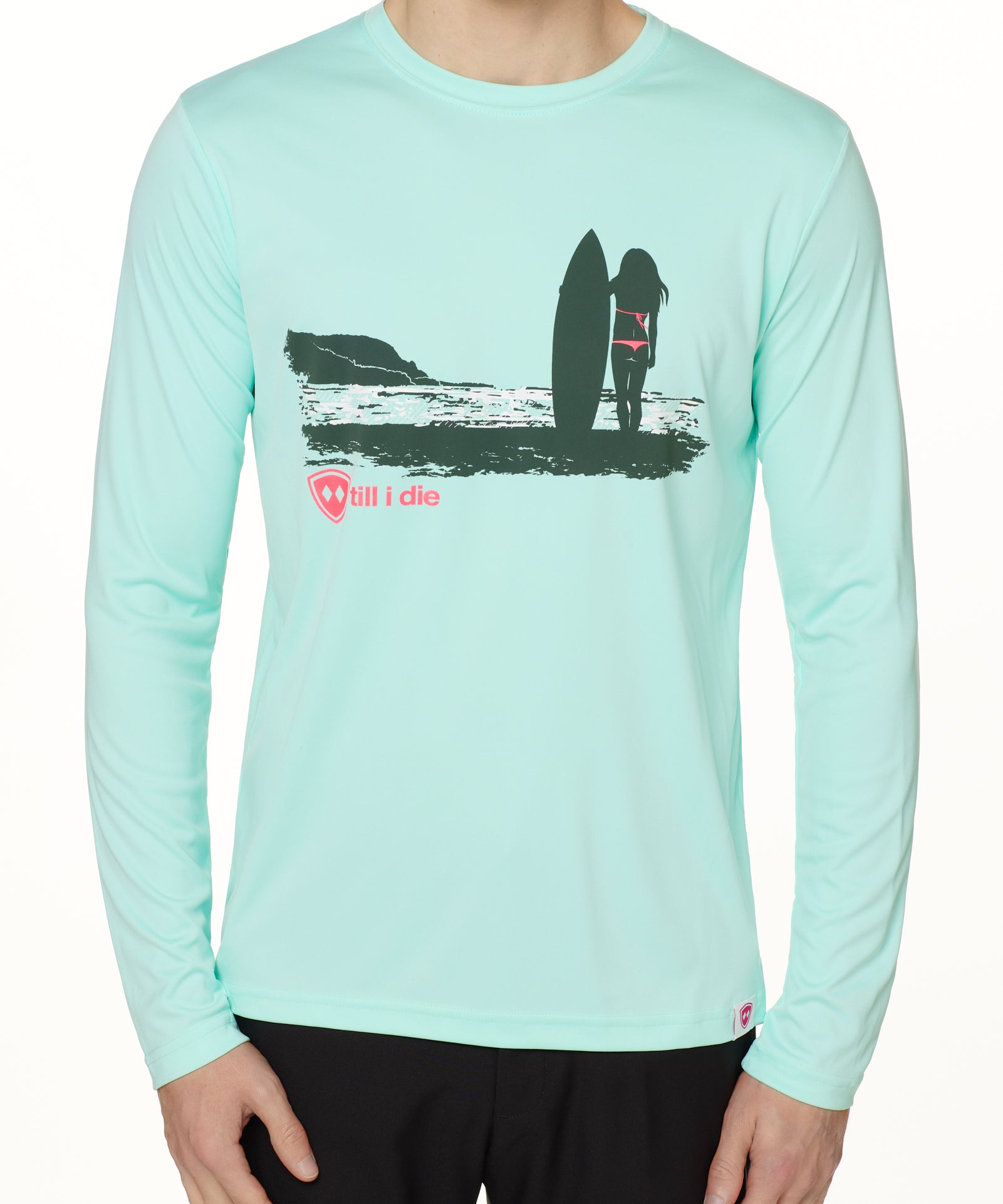 Front view of a male model wearing the Surf Girl long sleeve performance shirt in mint, shown on a white background. The graphic depicts a silhouetted female surfer standing with her board, gazing out at the ocean surf, with a hot pink “Till I Die” logo below the artwork.