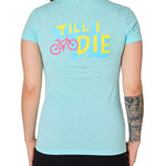 Back view of a female model wearing the Bike till i die tee shirt in cancun blue on a white background. The graphic features a pink mountain bike layered over bold blue and yellow till i die text