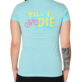 Back view of a female model wearing the Bike till i die tee shirt in cancun blue on a white background. The graphic features a pink mountain bike layered over bold blue and yellow till i die text