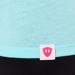 Close-up detail of a pink Double Diamond Shield woven hem label on a Cancun blue tee shirt.