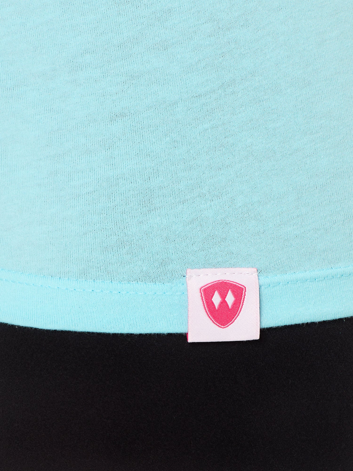 Close-up detail of a pink Double Diamond Shield woven hem label on a Cancun blue tee shirt.