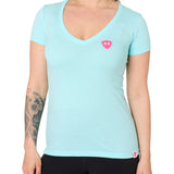 Front view of a female model wearing the Till I Die Bike V-Neck Tee in Cancun Blue on a white background. The shirt features a pink Double Diamond Shield logo on the wearer's left chest.
