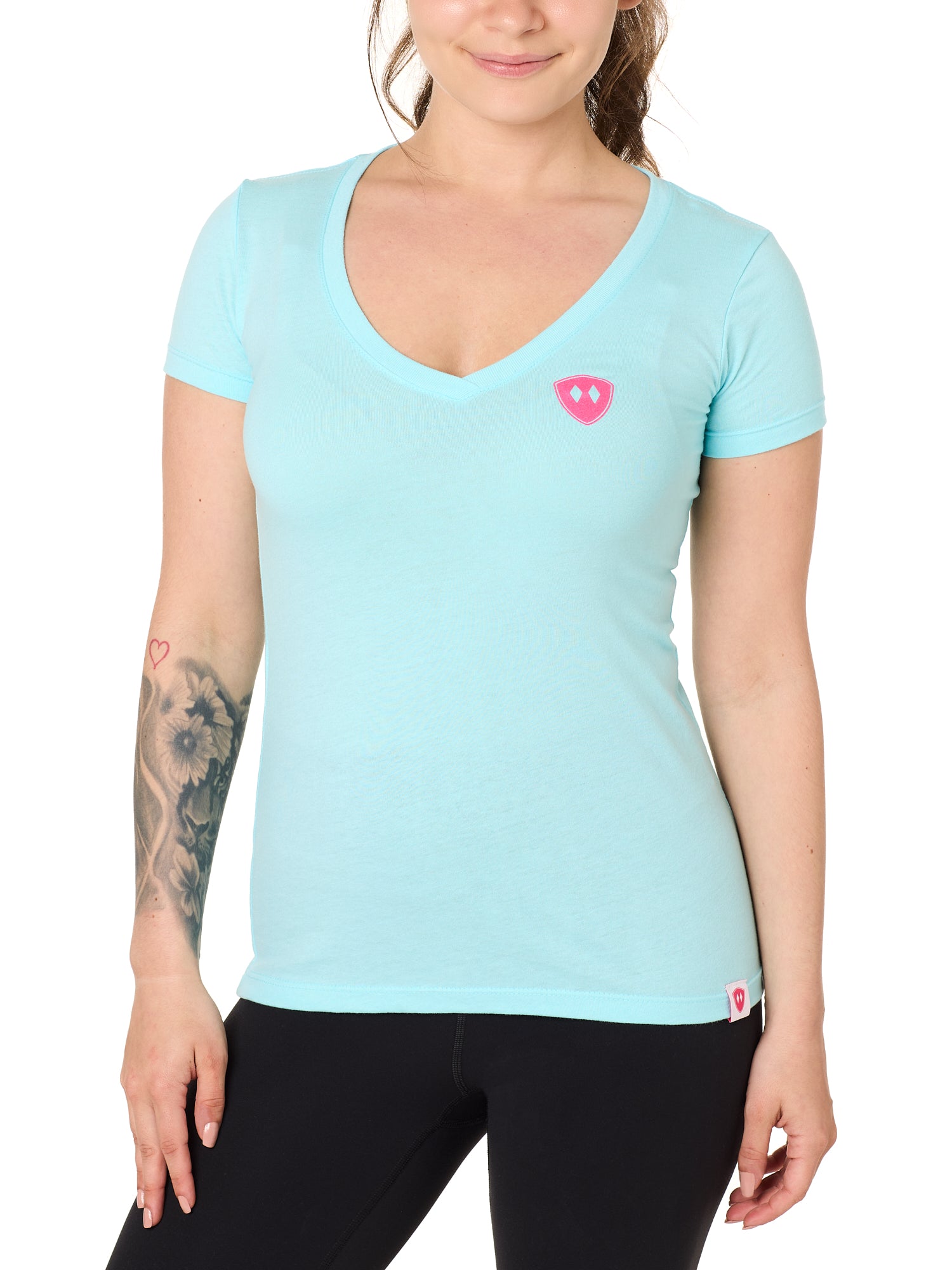 Front view of a female model wearing the Till I Die Bike V-Neck Tee in Cancun Blue on a white background. The shirt features a pink Double Diamond Shield logo on the wearer's left chest.