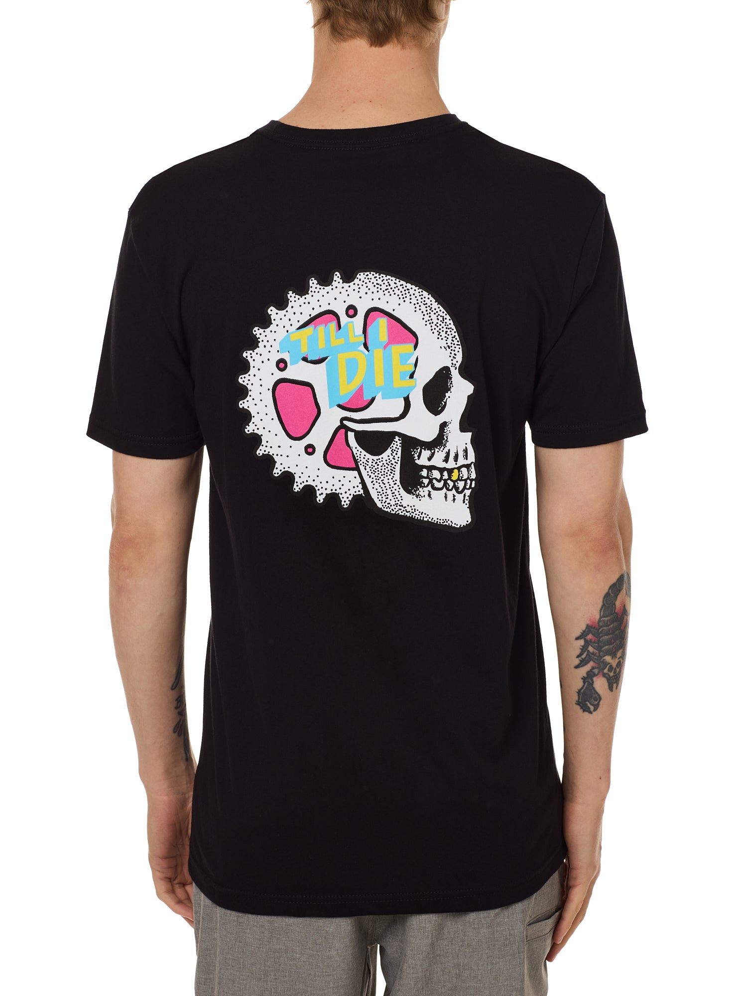 Back view of a male model wearing the Gear Head Tee in black. The back graphic features a skull with gears inside the head and overlapped by yellow and blue "Till I Die" text.