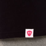 Close-up detail of a pink Double Diamond Shield woven hem label on a black shirt.