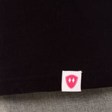 Close-up detail of a pink Double Diamond Shield woven hem label on a black shirt.