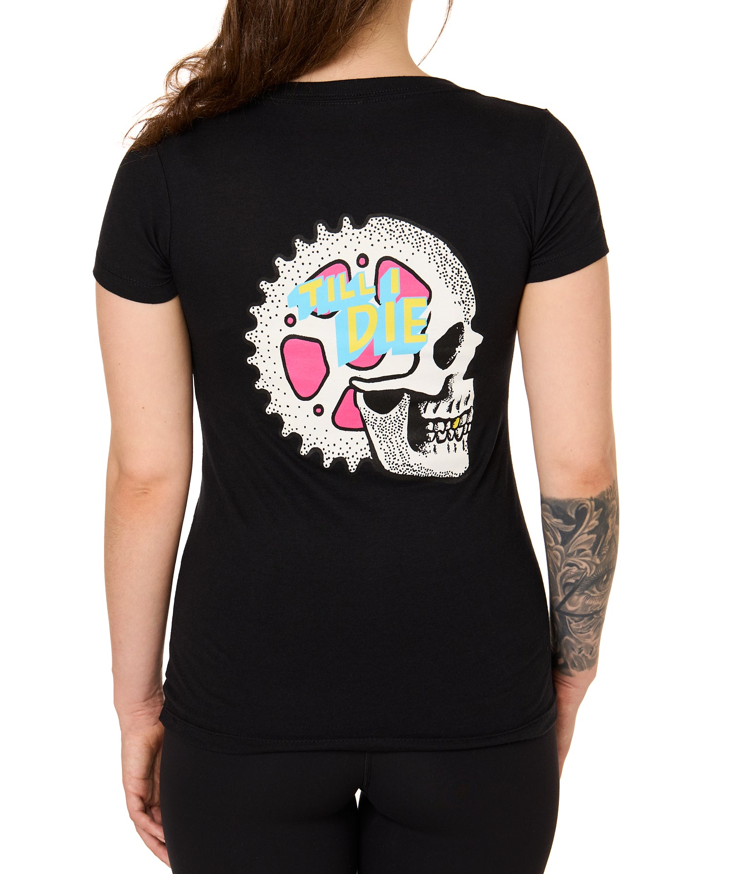 Back view of a female model wearing the Gear Head Tee in black. The back graphic features a skull with gears inside the head and overlapped by yellow and blue "Till I Die" text.
