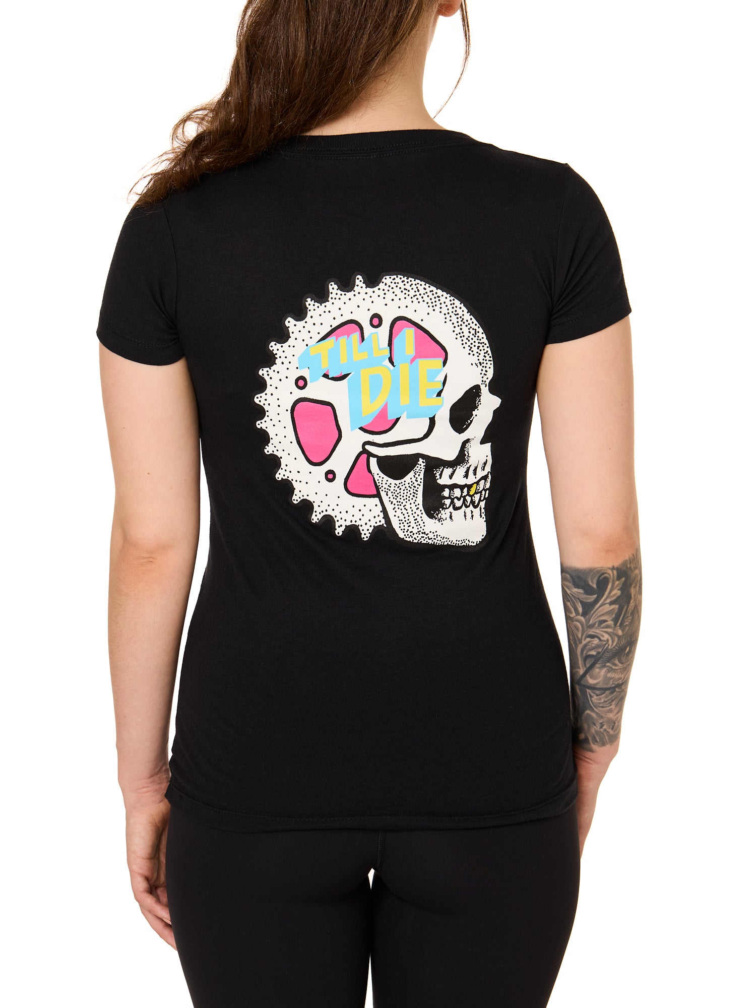 Back view of a female model wearing the Gear Head Tee in black. The back graphic features a skull with gears inside the head and overlapped by yellow and blue "Till I Die" text.