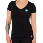 Front view of a female model wearing the Gear Head V neck tee in black on a white background. Accented with a cyan blue double diamond shield over wearers left chest.