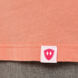 Close-up detail of a pink Double Diamond Shield woven hem label on a sunset short sleeve shirt.