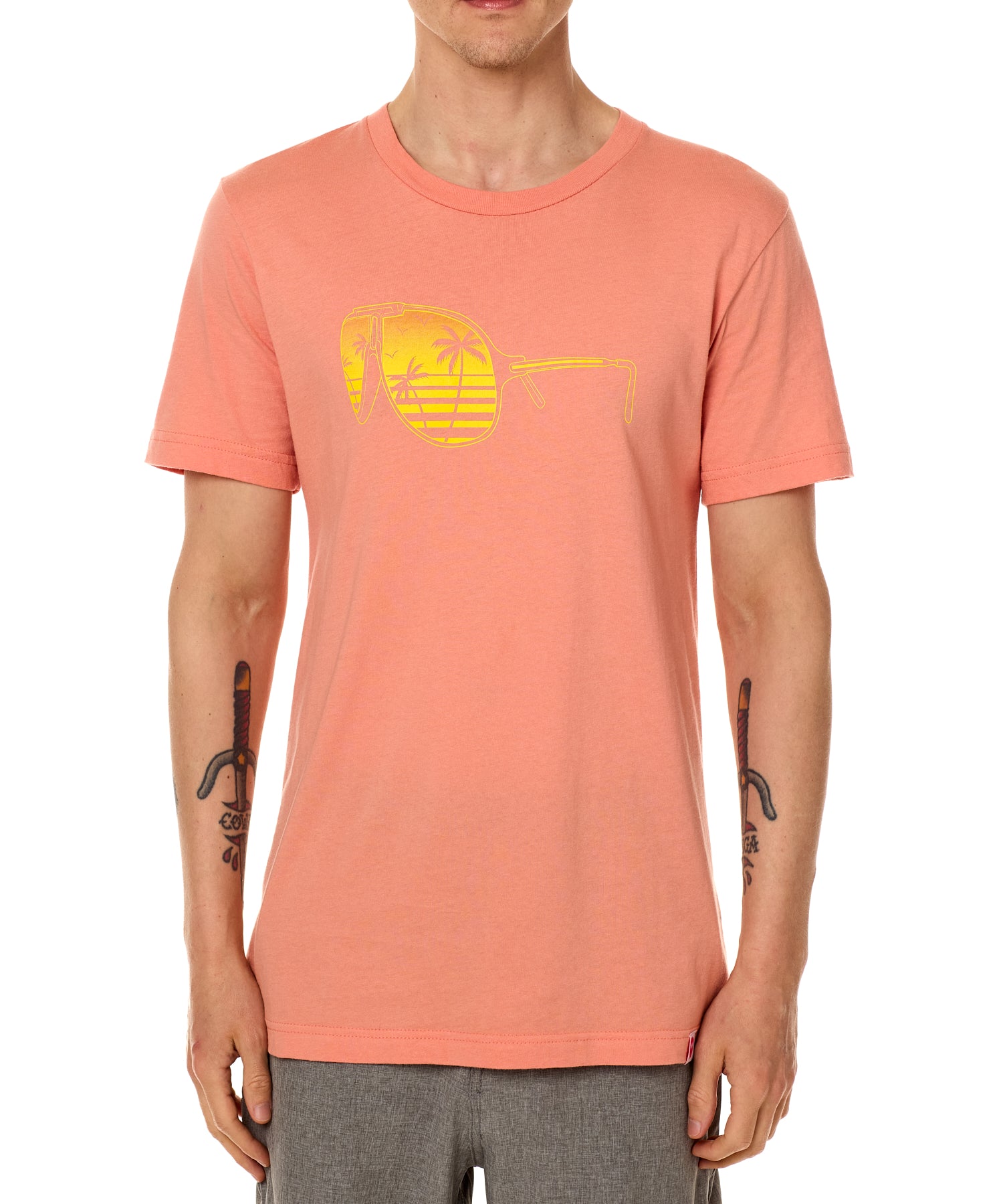 Front view of a male model wearing a short sleeve crew neck Sunset T-Shirt. The graphic features a yellow print of sunglasses with a tropical beach scene reflected in the lenses.