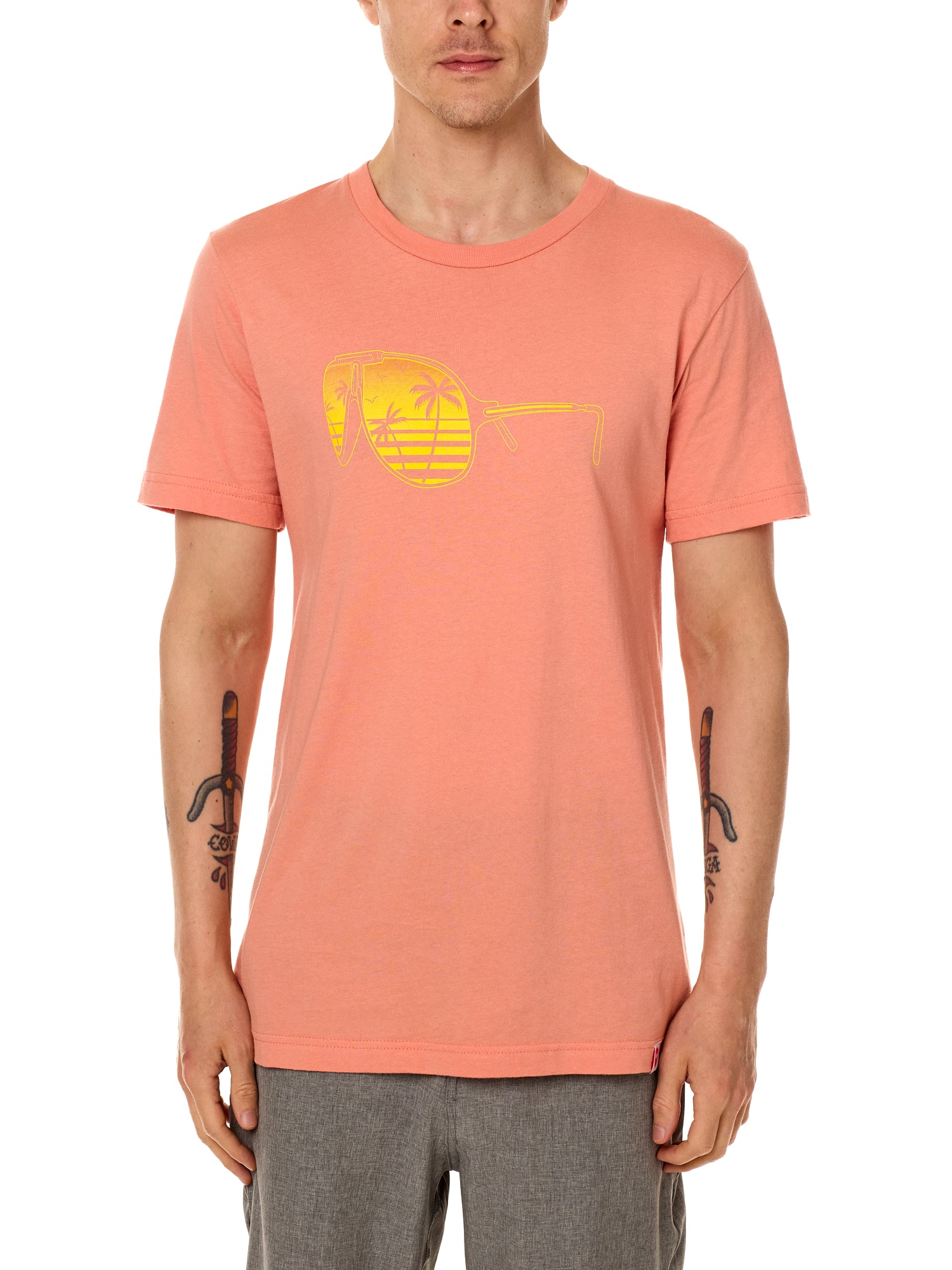 Front view of a male model wearing a short sleeve crew neck Sunset T-Shirt. The graphic features a yellow print of sunglasses with a tropical beach scene reflected in the lenses.