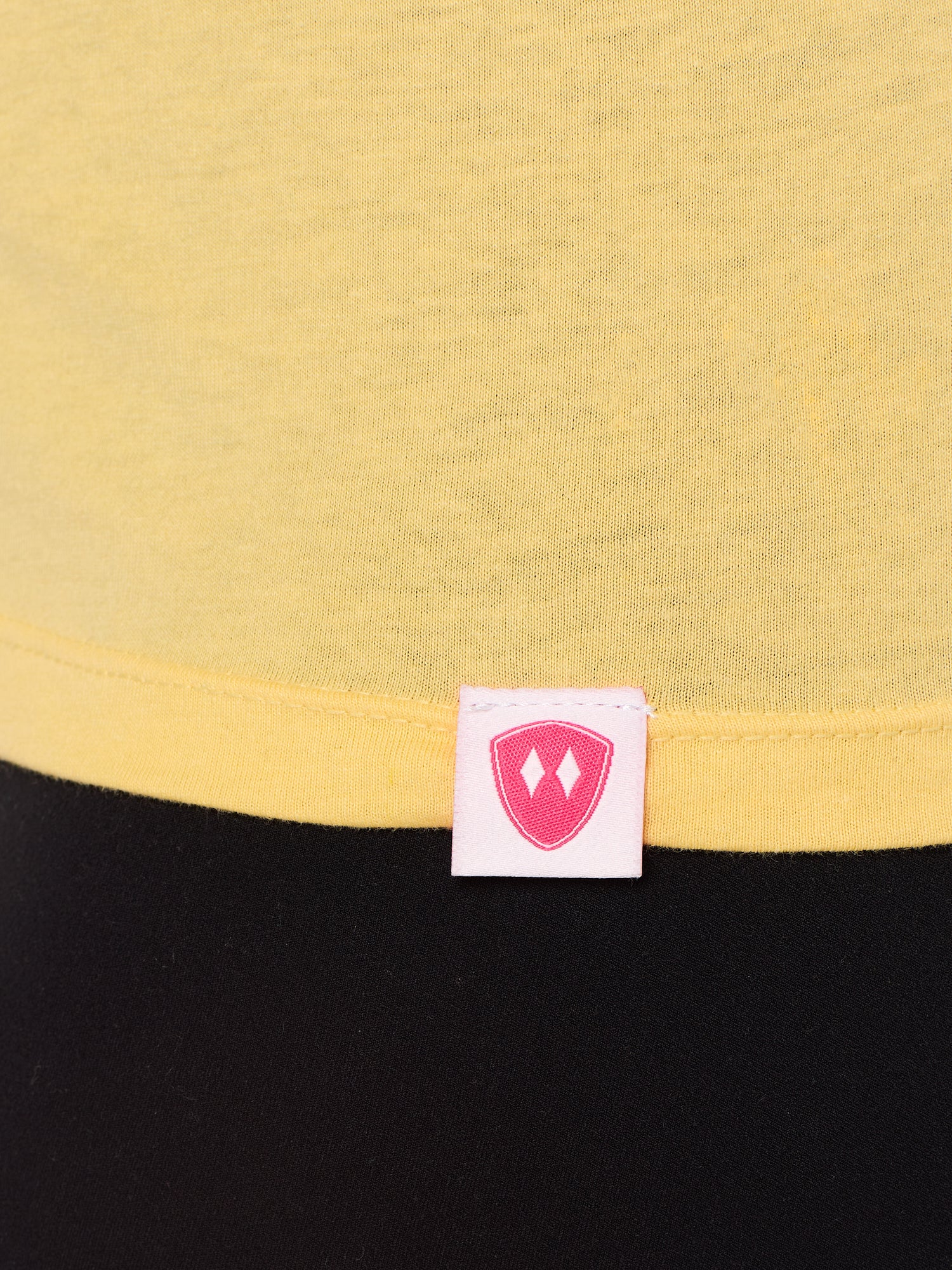 Close-up detail of a pink Double Diamond Shield woven hem label on a banana shirt.