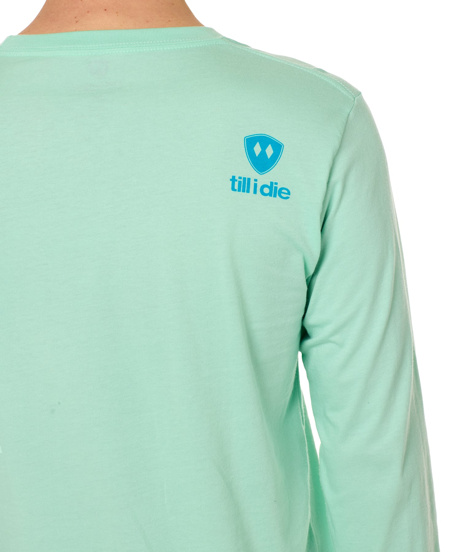 Back view of a male model wearing a Mint Green long sleeve shirt on a white background, featuring a blue Till I Die logo on the wearer’s top right shoulder.
