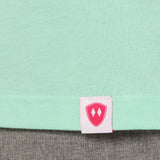Close-up detail of a pink Double Diamond Shield woven hem label on a mint green shirt.