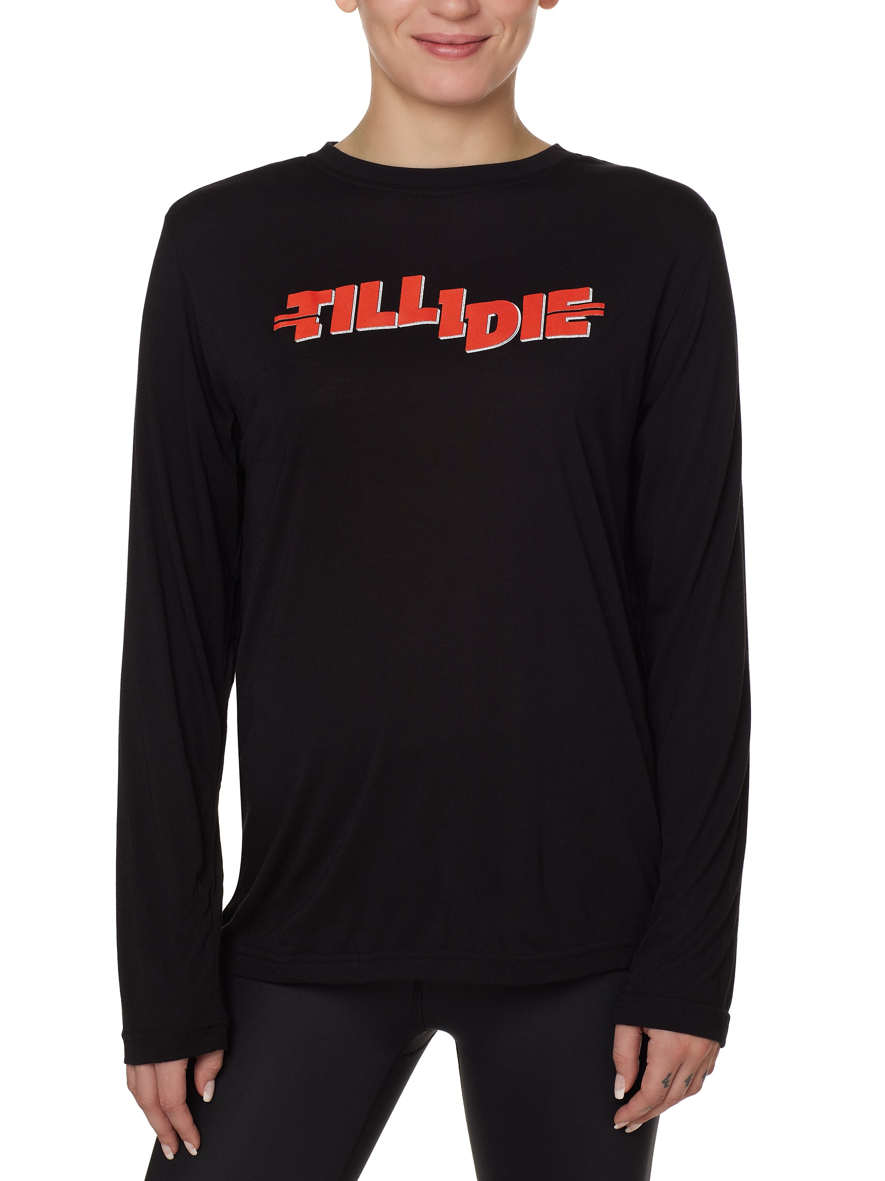 front view of a female model wearing the hot dog crew neck long sleeve tee in black. The graphic is red 'till i die' lettering inspired by the iconic title art for the 1984 ski move 'Hot Dog'