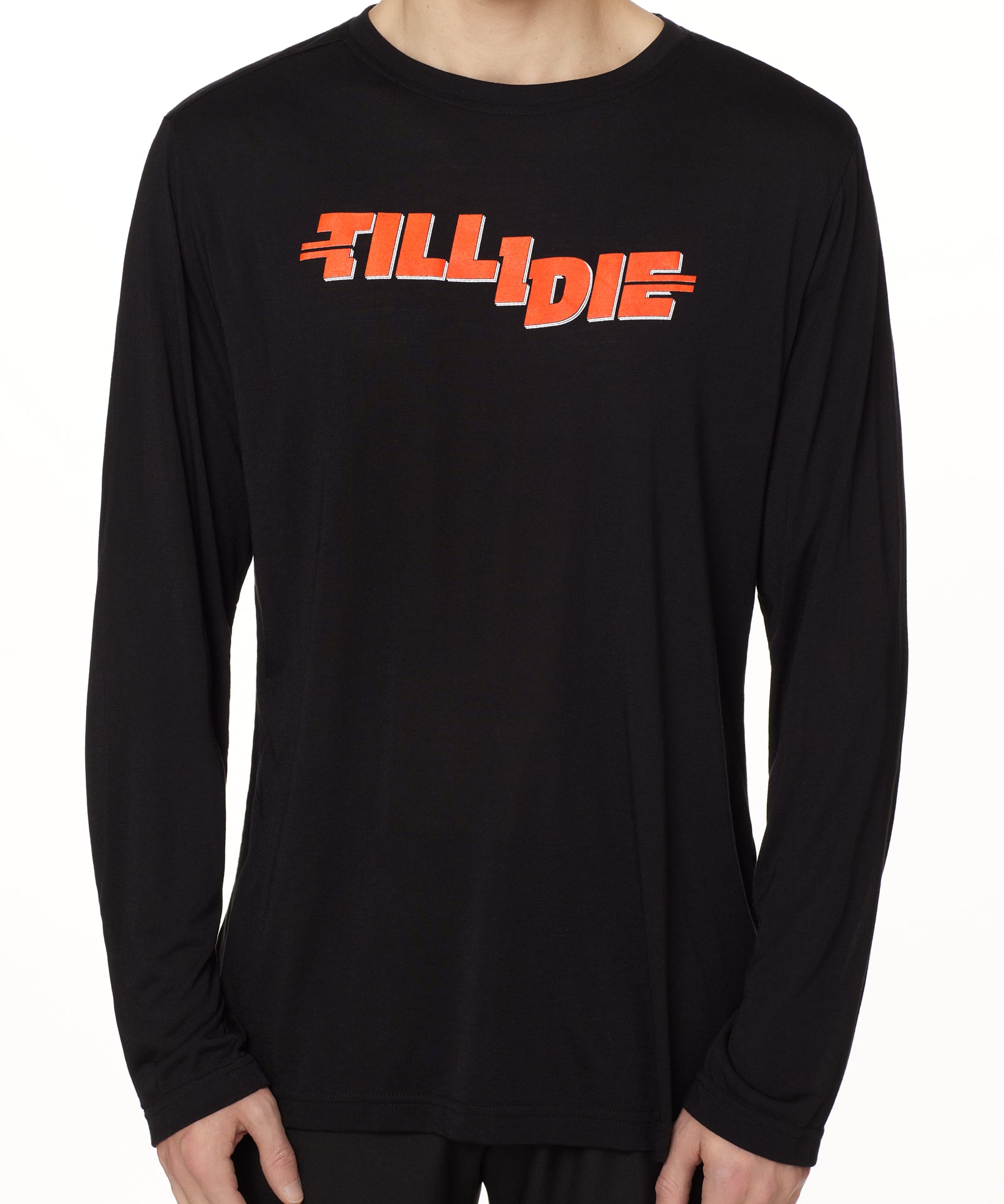 front view of a male model wearing the hot dog crew neck long sleeve tee in black. The graphic is red 'till i die' lettering inspired by the iconic title art for the 1984 ski move 'Hot Dog'