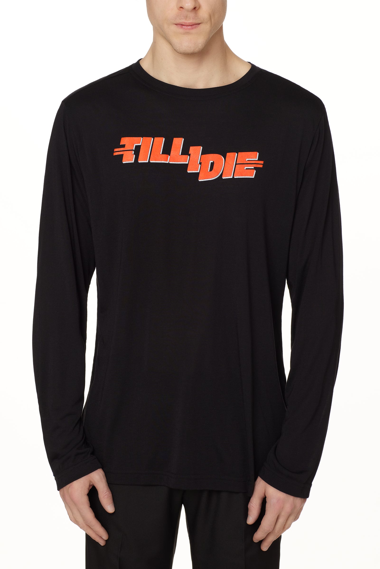front view of a male model wearing the hot dog crew neck long sleeve tee in black. The graphic is red 'till i die' lettering inspired by the iconic title art for the 1984 ski move 'Hot Dog'