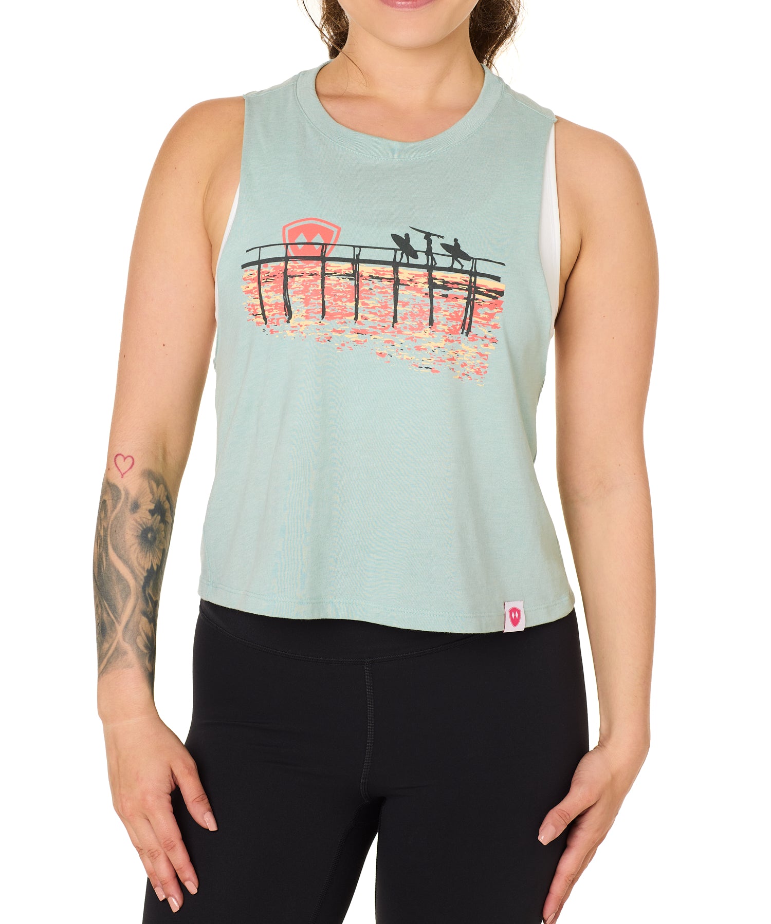 Front view of a female model wearing the Endless Summer tank in dusty blue, displayed on a white background. The graphic features three silhouetted surfers walking along an ocean boardwalk, with a setting sun—stylized as the Till I Die double diamond shield—glowing in the background.