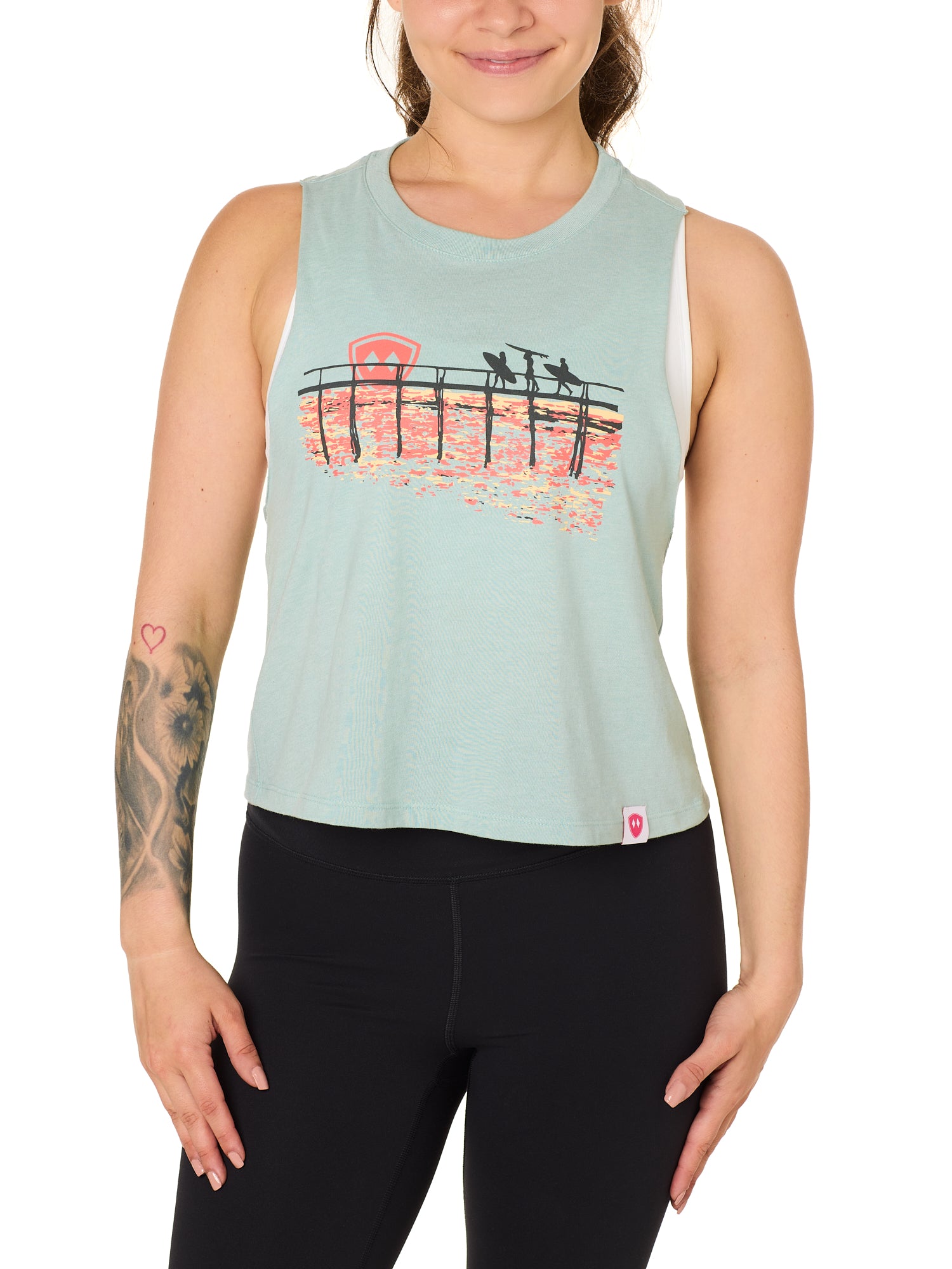 Front view of a female model wearing the Endless Summer tank in dusty blue, displayed on a white background. The graphic features three silhouetted surfers walking along an ocean boardwalk, with a setting sun—stylized as the Till I Die double diamond shield—glowing in the background.