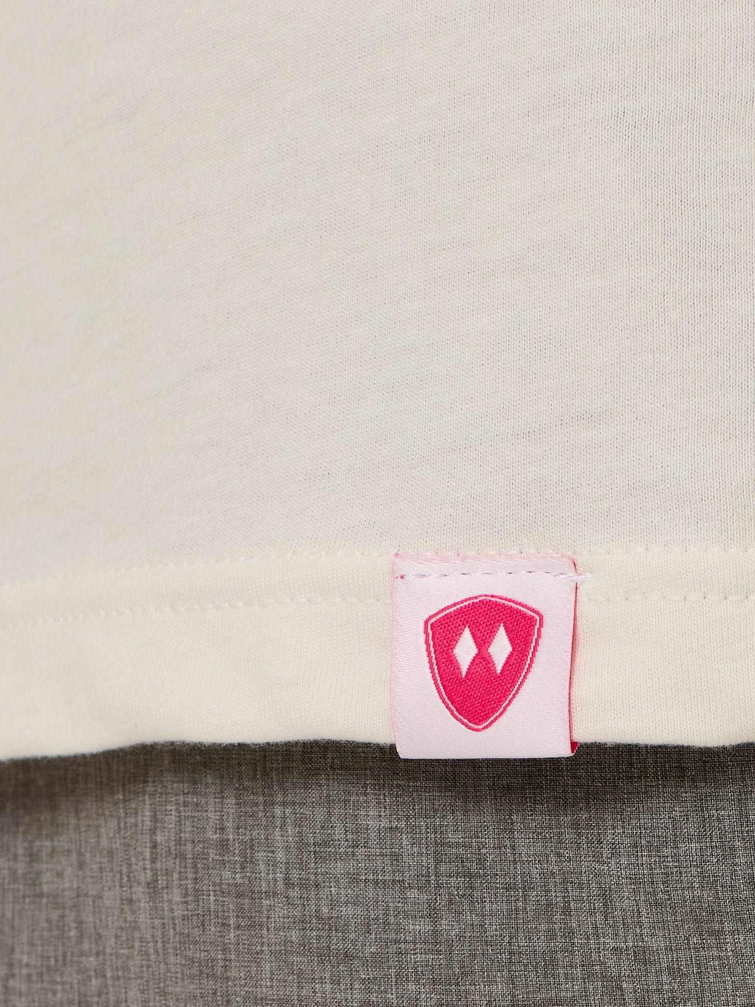 Close-up detail of a pink Double Diamond Shield woven hem label on a vintage white crew neck tee.