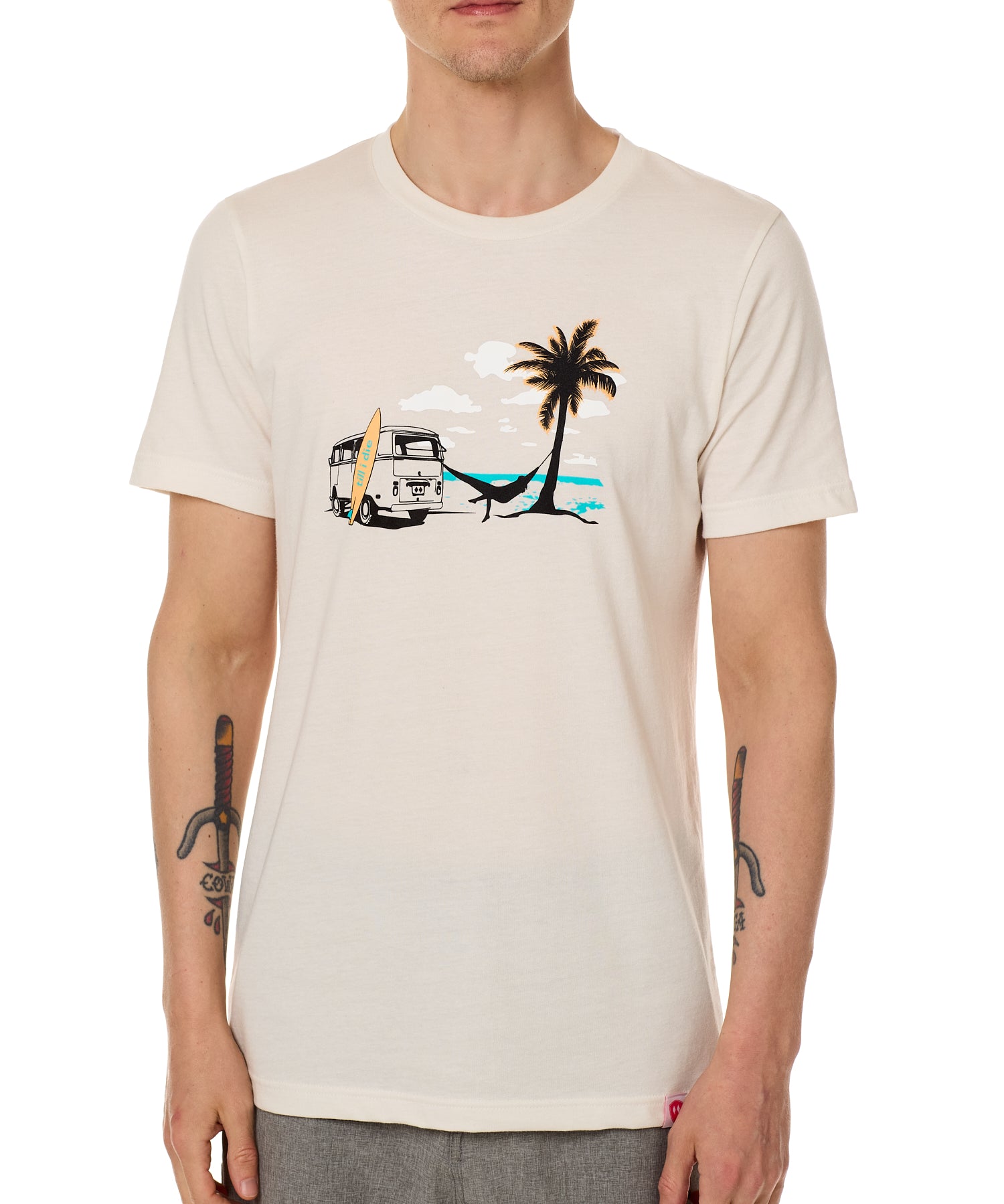 Front view of a male model wearing the Hammock crew neck tee in vintage white, displayed on a white background. The graphic depicts a vintage VW bus parked on a beach, with a surfboard leaning against it and a silhouetted figure relaxing in a hammock strung between the van and a palm tree.