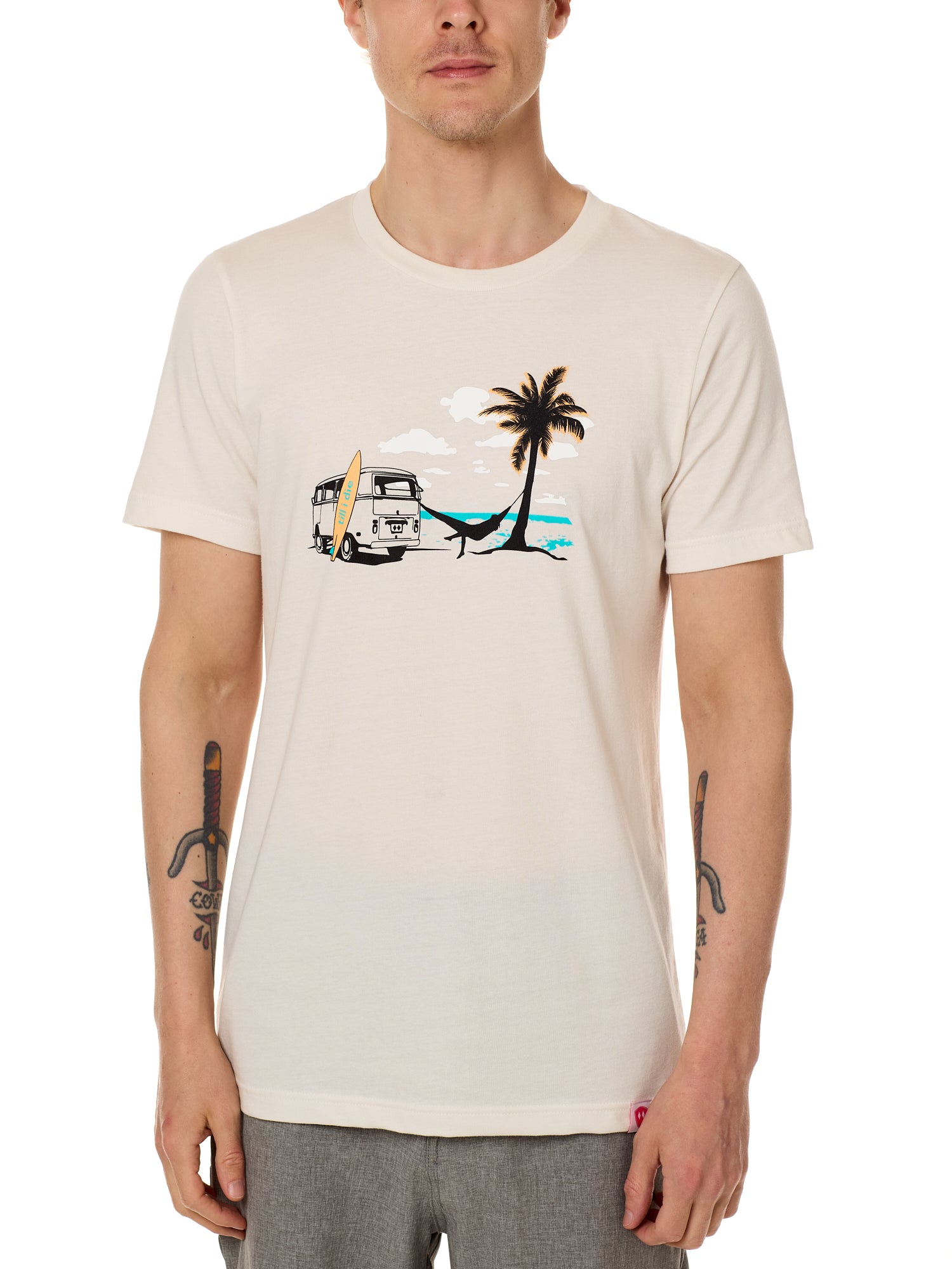 Front view of a male model wearing the Hammock crew neck tee in vintage white, displayed on a white background. The graphic depicts a vintage VW bus parked on a beach, with a surfboard leaning against it and a silhouetted figure relaxing in a hammock strung between the van and a palm tree.