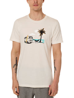 Front view of a male model wearing the Hammock crew neck tee in vintage white, displayed on a white background. The graphic depicts a vintage VW bus parked on a beach, with a surfboard leaning against it and a silhouetted figure relaxing in a hammock strung between the van and a palm tree.
