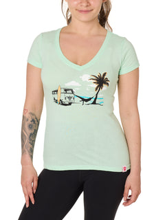 Front view of a female model wearing the Hammock V-neck tee in mint, displayed on a white background. The graphic depicts a vintage VW bus parked on a beach, with a surfboard leaning against it and a silhouetted figure relaxing in a hammock strung between the van and a palm tree.