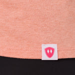 Close-up detail of a pink Double Diamond Shield woven hem label on a sunset tank.