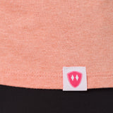 Close-up detail of a pink Double Diamond Shield woven hem label on a sunset tank.